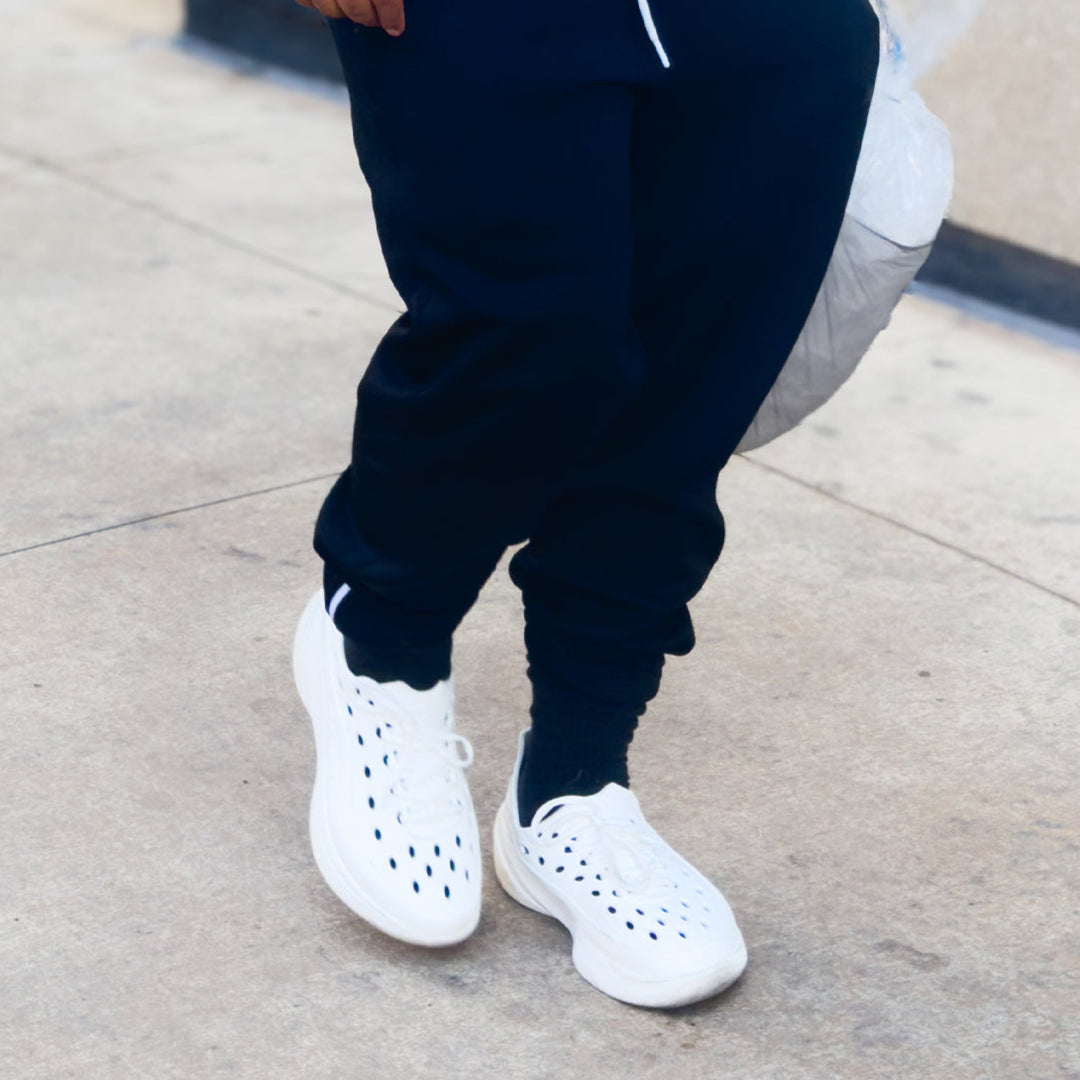 Model wearing white Somexc recovery sneaker with black sweats on street#color_white